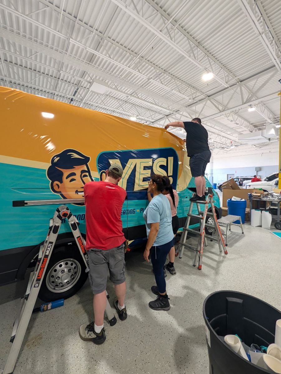 Crew wrapping a cargo van, front to back
